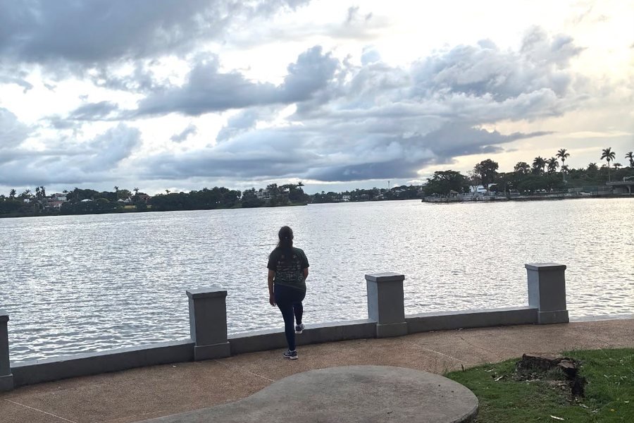 Mulher caminhando sozinha à beira da lagoa em um fim de tarde